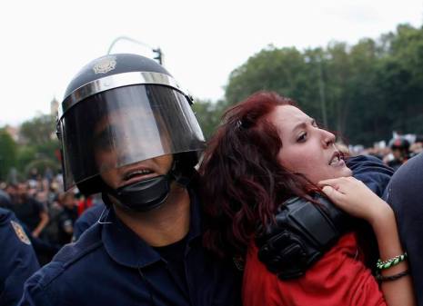 Protester grimaces as she is dragged away by riot police outside Spanish parliament in Madrid